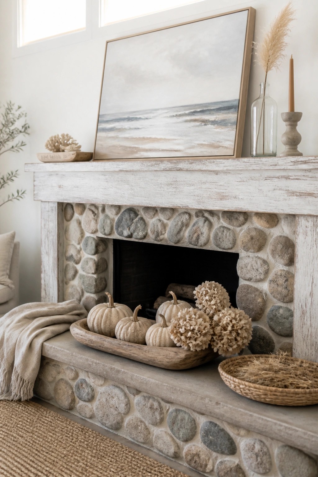 Whitewashed mantel fireplace with pumpkins, dried hydrangeas, ocean painting, and neutral decor