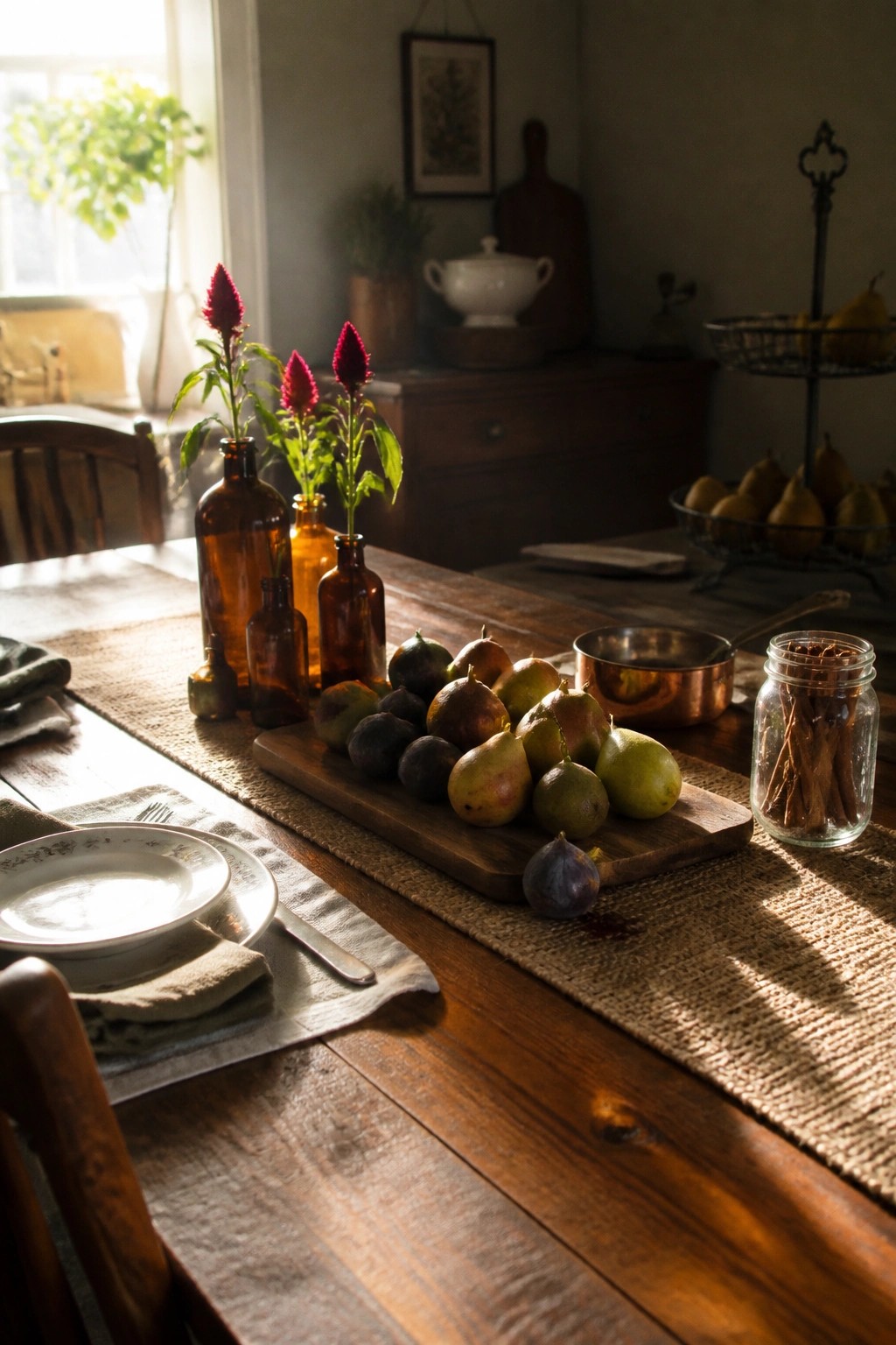 Rustic wooden table with figs, pears, red flowers in amber bottles, and burlap runner.