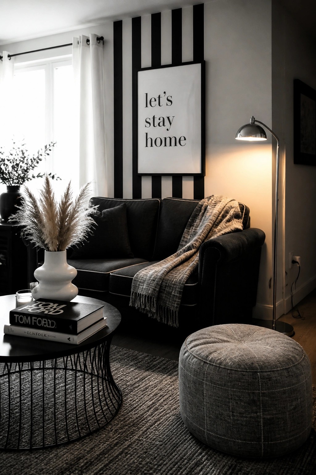 Cozy monochromatic living room with black sofa, striped wall, and 