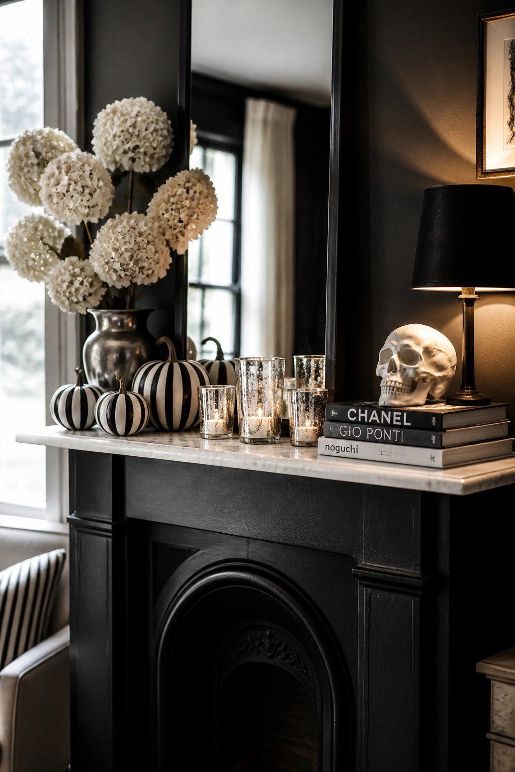 Black fireplace mantel with striped pumpkins, white flowers, skull, books, and candles.