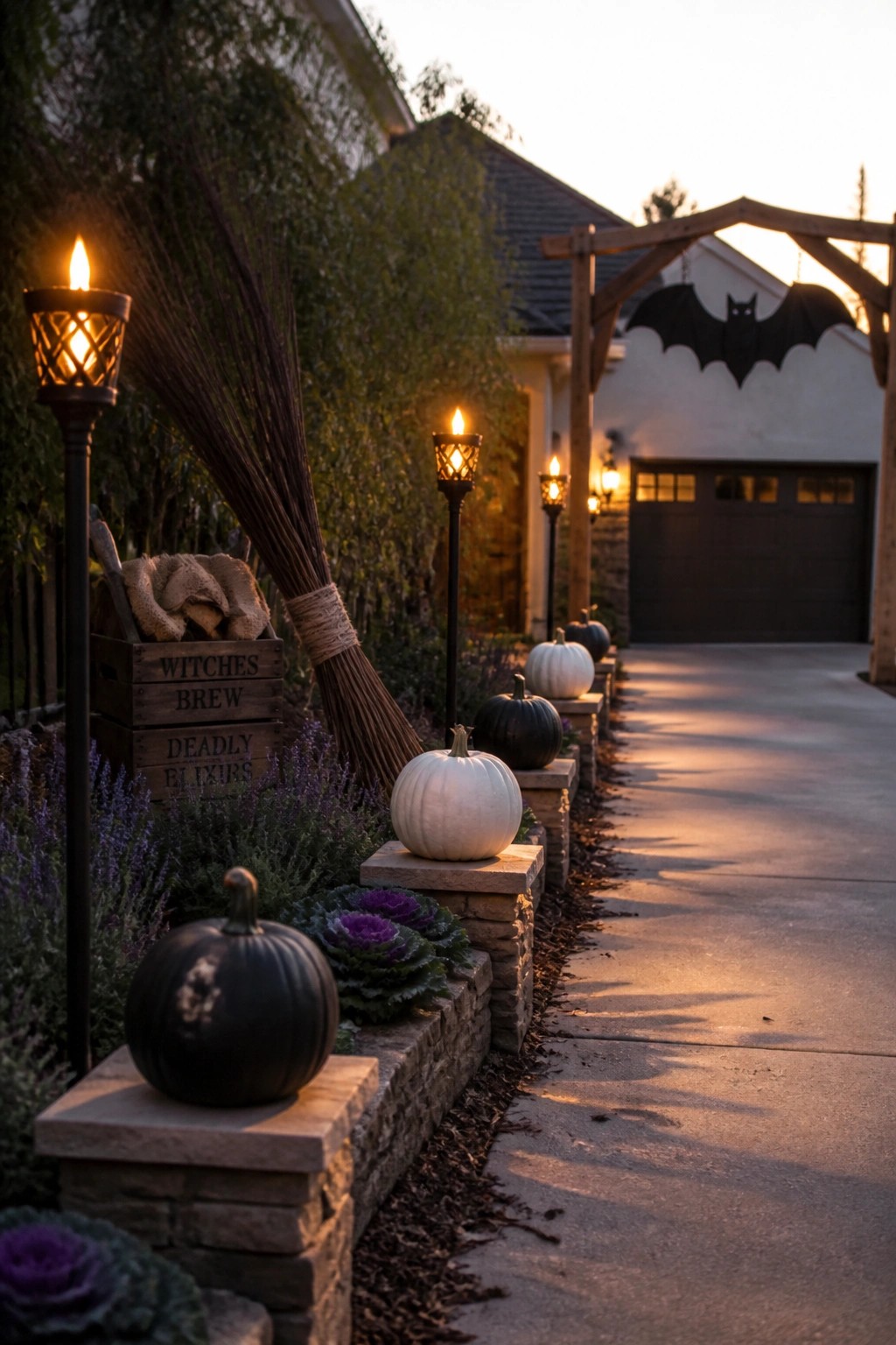Glowing lanterns, pumpkins, broom, and bat silhouette line a twilight driveway.